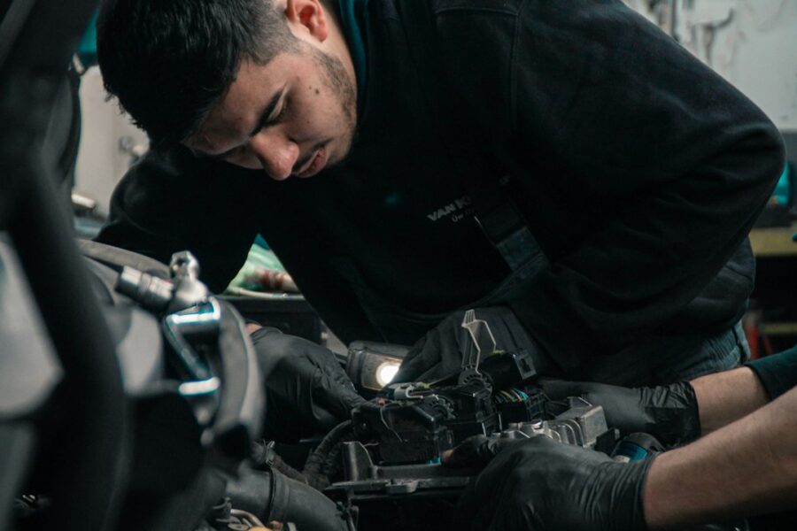 Meccanico al lavoro sul motore di un'auto usata in officina
