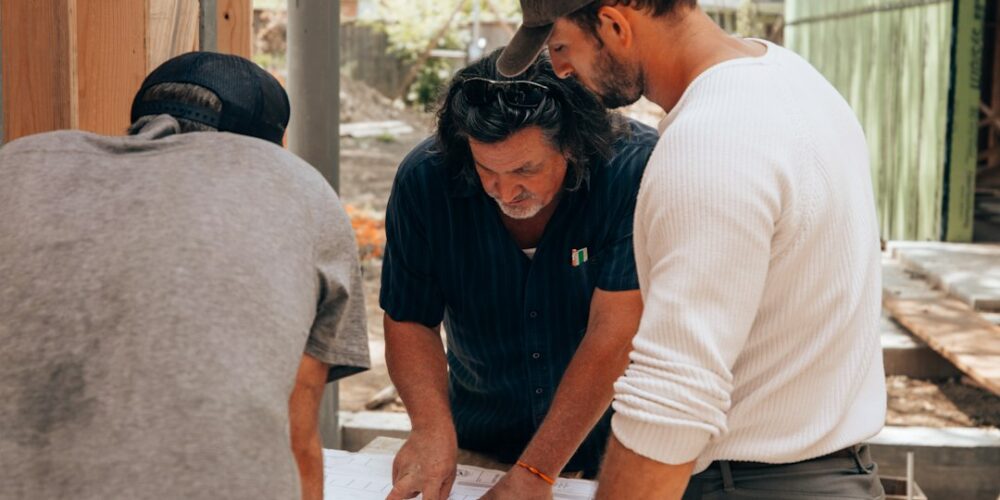 Tecnici che confrontano planimetrie e documenti durante lavori edilizi
